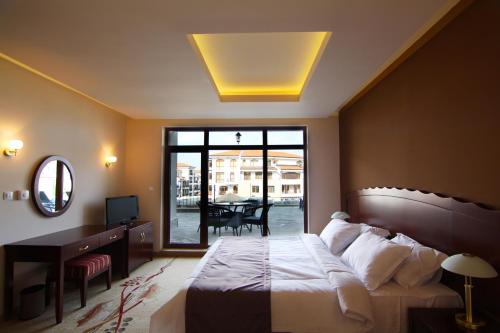ein Schlafzimmer mit Bett, Schreibtisch und Fenster in der Unterkunft The Vineyards Boutique Hotel & SPA in Aheloy