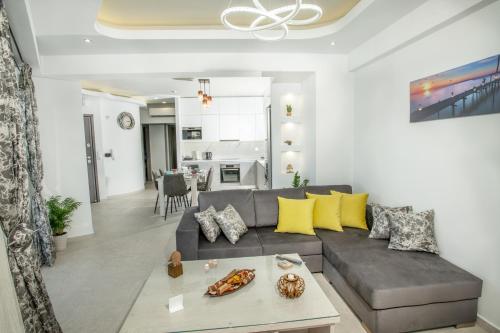 sala de estar con sofá gris y almohadas amarillas en Elmaky Luxury Apartments en Palaiokastro