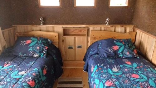 two beds in a small room with two windows at Complejo Cabañas Quilamalen in Villarrica