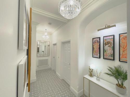 a hallway with white walls and a chandelier at Selworthy - Luxury 3 Bedroom Apartment in Yeovil