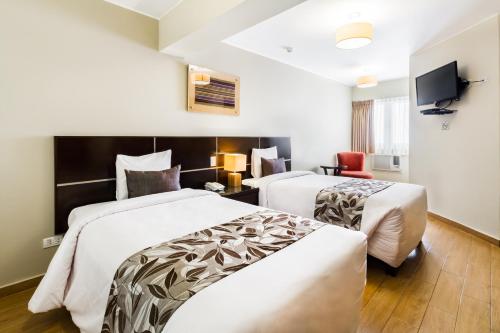 a hotel room with two beds and a tv at Hotel El Tambo 2 in Lima