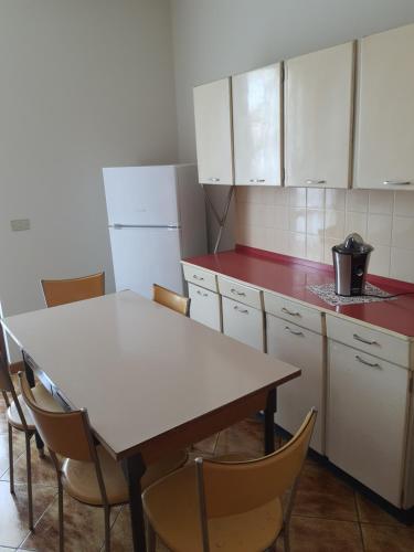 una cucina con armadi bianchi, tavolo e sedie di Ida Garda See a Castelnuovo del Garda