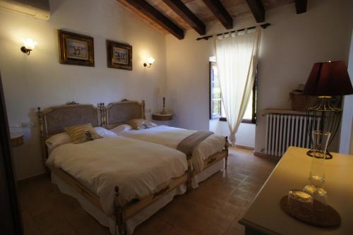 a bedroom with two beds and a table and a window at El Encinar de Arta in Artá