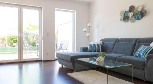 a living room with a blue couch and a glass table at Domizil Illmitz in Illmitz