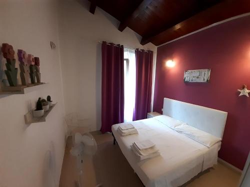 a small bedroom with a white bed with purple walls at Casale Angela in Torrevecchia Teatina