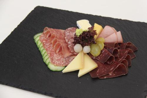 a plate of food with meats and cheese on it at Hotel Ambassador in Bern