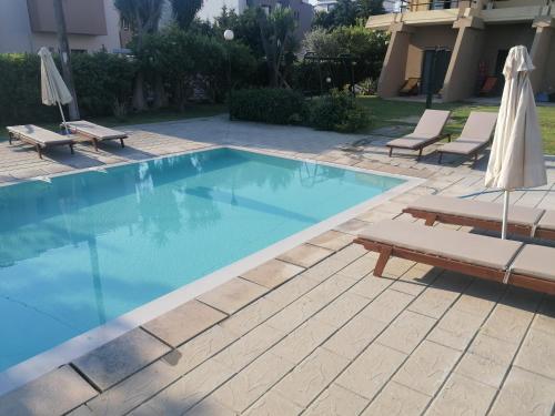 a swimming pool with two lounge chairs and an umbrella at Endless Summer Pool Flat in Ixia