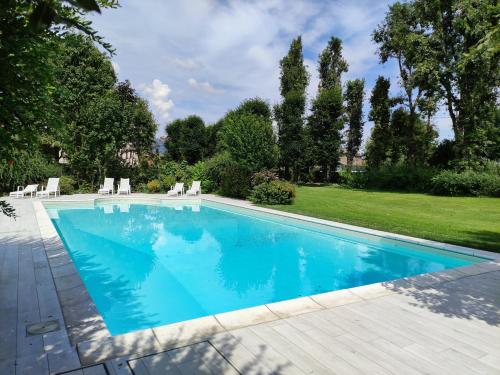 a swimming pool with blue water in a yard at B&B Villa Valchero in Carpaneto Piacentino