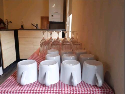 a table with white cups and wine glasses on it at Charmante maison lumineuse au coeur de Liège! in Ans
