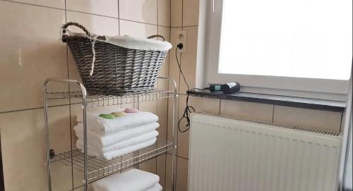 a towel rack with towels and a basket in a bathroom at Charmante maison lumineuse au coeur de Liège! in Ans