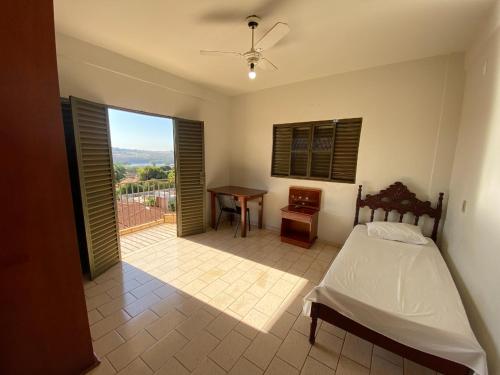 ein Schlafzimmer mit Bett, Schreibtisch und Fenster in der Unterkunft Império Hotel in Caçu