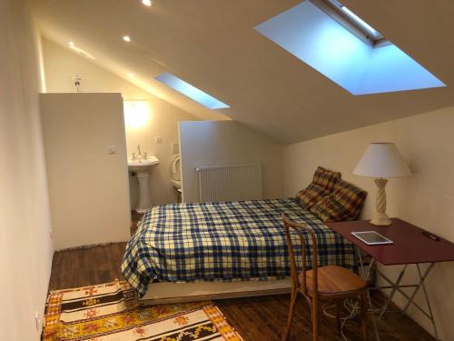 - une chambre avec un lit, un bureau et une lucarne dans l'établissement Les volets bleus, à Gresse-en-Vercors