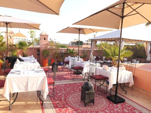 a restaurant with white tables and umbrellas at Arabian Riad Marrakech in Marrakesh