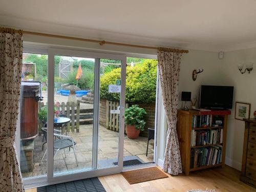 une porte coulissante en verre menant à une terrasse avec une table. dans l'établissement Lane End Cottage, à Ovington