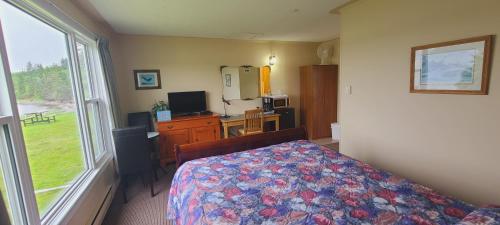 a bedroom with a bed and a desk and a window at St Ann's Motel & Cottage in Baddeck