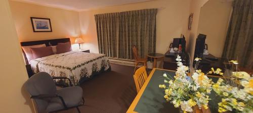a hotel room with a bed and a table with flowers at St Ann's Motel & Cottage in Baddeck