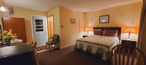 a bedroom with a bed and a desk with two lamps at St Ann's Motel & Cottage in Baddeck