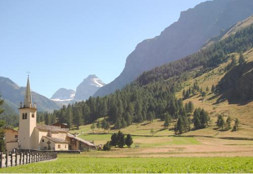 a church in a field with mountains in the background at Appartamenti Edelweiss in Chaudana