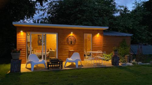 a small shed with white chairs and a table at Les mouettes - la paix du bord de Seine in Berville-sur-Seine