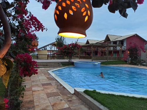 a person swimming in a swimming pool with a light fixture at ChaleVille coqueiro - Chalé 2101 in Luis Correia