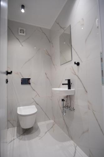 a white bathroom with a toilet and a sink at Solis Apartments Bol in Bol