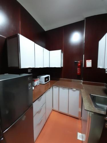 a kitchen with white cabinets and a stainless steel refrigerator at EMAN HOUSE in Salalah