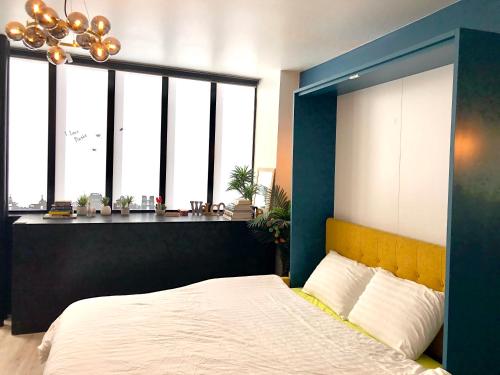 - une chambre avec un lit doté d'une tête de lit bleue et de fenêtres dans l'établissement Relais Cocorico Fondary Apartment Eiffel Tower District, à Paris