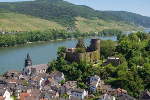 a town with a castle in the middle of a river at Rheintal-Ferien - 90 qm Ferienwohnung mit Wine & Style - Dein Urlaub am Rhein in Niederheimbach