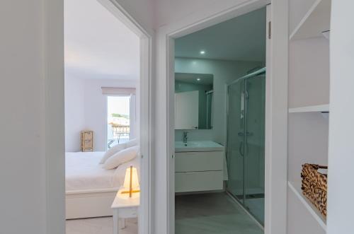 a bedroom with a bed and a shower and a sink at Apartamento holidays in Cala en Porter