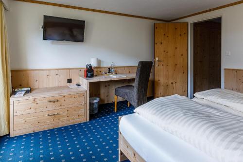 a bedroom with a bed and a desk and a sink at Landgasthof Sternen in Bühler