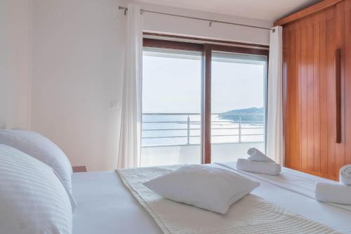 a bedroom with a white bed with a large window at Villa Zorka in Omiš