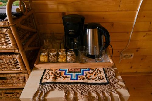 a counter with a coffee pot and some glasses at Cuibul Vulturilor - Casuta in Copac in Moisei