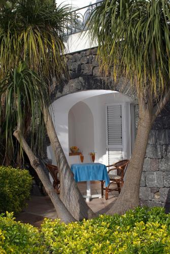 a table and chairs under a stone wall with a tree at Hotel Terme Villa Teresa in Ischia