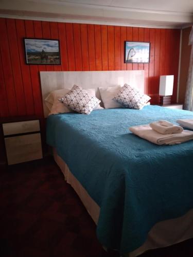 a bedroom with a large blue bed with red walls at hostal geminis ,phillipi 653 centro in Puerto Natales
