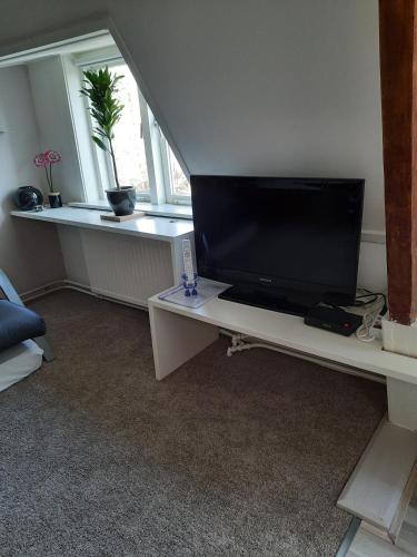 a living room with a flat screen tv on a white table at B&B De Goffert in Nijmegen