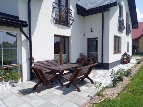 a patio with two benches and a wooden table at Zagroda na Borach in Jabłonka