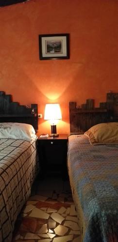 a bedroom with two beds and a lamp on a table at Portal de los Farolitos in Concepción de Ataco