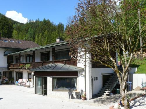 ein großes Gebäude mit einer Veranda und einem Baum in der Unterkunft Gästehaus Friedlich in Schönau am Königssee