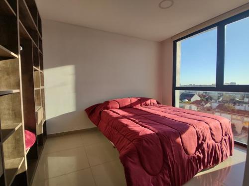 um quarto com uma cama vermelha num quarto com uma janela em Frente al mar charlone em Mar del Plata