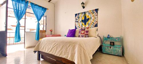 1 dormitorio con 1 cama con cortinas azules en Family Host HOSTEL en Villa de Leyva