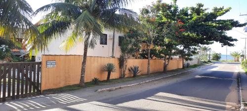 a house on a street with a fence and palm trees at Chale Buzios Praia Rasa in Búzios