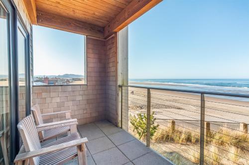 a balcony with two chairs and a view of the beach at Headlands Coastal Lodge & Spa in Pacific City
