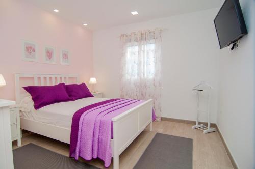 een witte slaapkamer met een paarse deken op een bed bij La Huerta de Manuel in Tejina