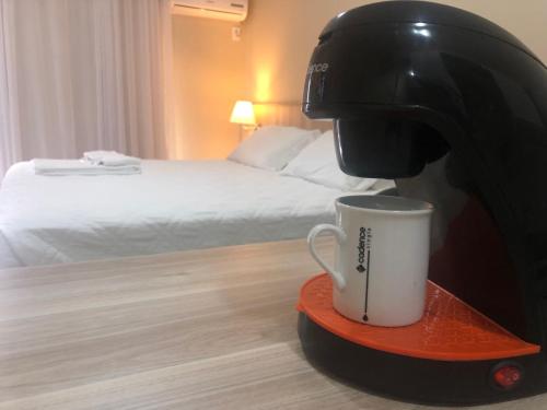 a coffee machine with a cup on a plate in a hotel room at Aquarius Flat Aptos e Suítes in Santa Cruz do Sul