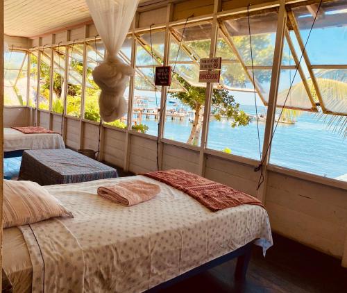 two beds in a room with a view of the water at Hotel La Casa Rosada in Lívingston