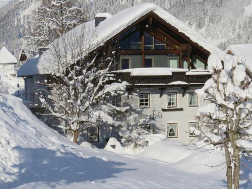 a house covered in snow with trees in front of it at Am Sonnenfels in Lermoos