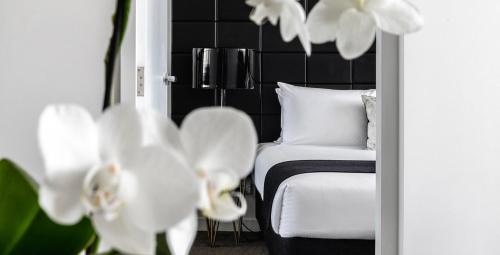 1 dormitorio con 1 cama, 1 silla y flores blancas en KOZYGURU Chatswood Luxury Studio NCH088-720, en Sídney