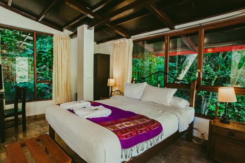 a bedroom with a large bed in front of windows at Rupa Rupa High Jungle Eco B&B in Machu Picchu