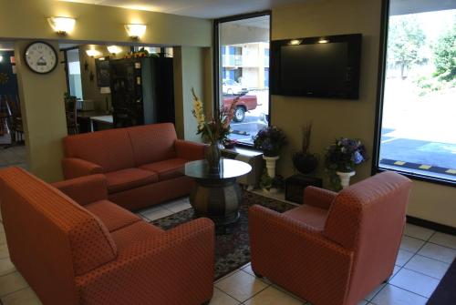 eine Lobby mit Stühlen, einem TV und einem Tisch in der Unterkunft Rodeway Inn Norcross in Norcross