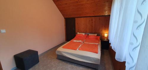 a small bedroom with a bed with orange sheets at Mária 93 in Balatonmáriafürdő